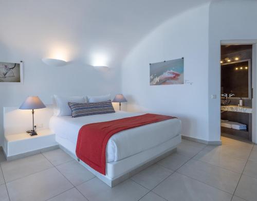 a white bedroom with a bed and a bathroom at Amber Light Villas in Imerovigli