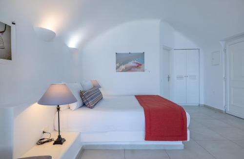 a white bedroom with a bed and a lamp at Amber Light Villas in Imerovigli