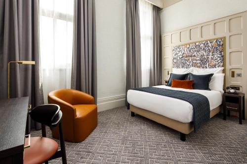 a hotel room with a bed and a chair at The Municipal Hotel Liverpool - MGallery in Liverpool