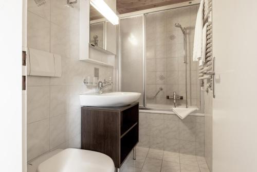 ein Bad mit einem Waschbecken, einem WC und einer Dusche in der Unterkunft Pension Arosa - Self Check-In in Arosa
