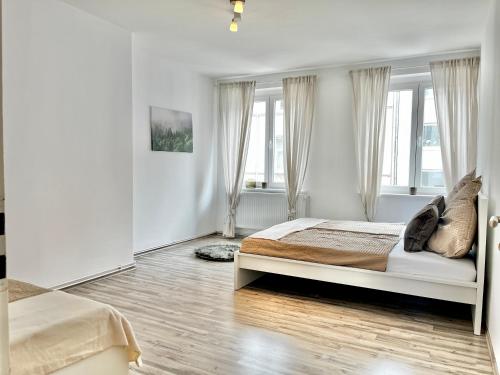 a white bedroom with a bed and windows at Design Apartment - Kingsize Bett - Küche - Zentral in Hannover