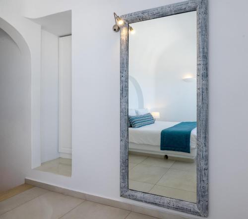 a mirror in a white room with a bed at Amber Light Villas in Imerovigli