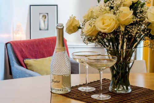 Una botella de champán y un jarrón de flores sobre una mesa. en Camden Town Duplex en Londres