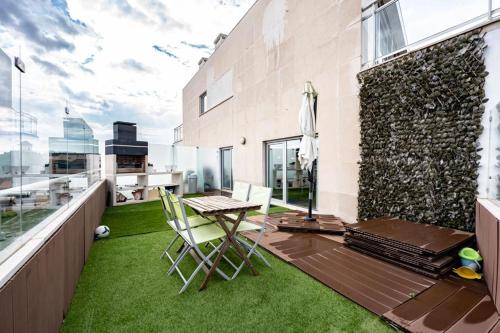 uma varanda com relva verde, uma mesa e cadeiras em Oasis beach apartment em Figueira da Foz