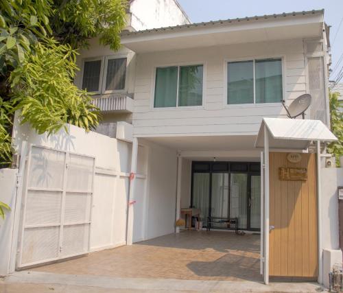 a white house with a gate and a door at Home Story Hostel Chiang Mai in Chiang Mai