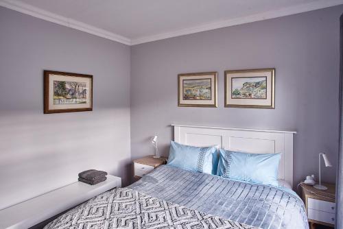 1 dormitorio con 1 cama y 2 cuadros en la pared en 2 The Mews - easy walk to town and the CVC en Clarens