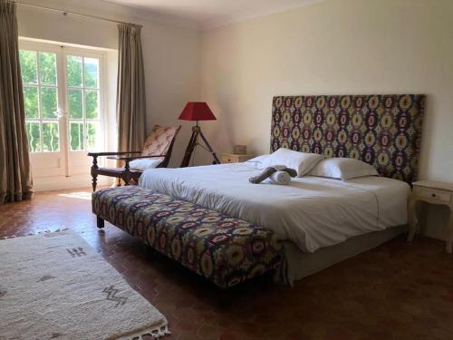ein Schlafzimmer mit einem großen Bett und einem Stuhl in der Unterkunft Merveilleuse Bastide Éco-responsable Château Réal d'Or in Gonfaron