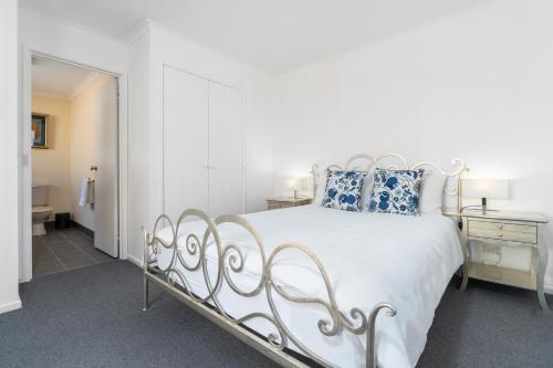 a white bed with blue pillows in a bedroom at Sunny Beach Holiday Home 80A in Kingston Beach