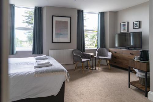 a bedroom with a bed and a flat screen tv at Sleepy Puffin Guest House in Tenby
