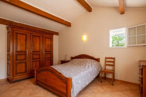 1 dormitorio con 1 cama y armario de madera en Les collins du sud 2, en Peyrolles-en-Provence