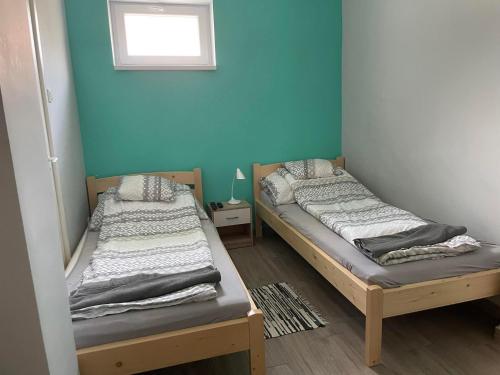2 camas en una habitación con una pared azul en ALFA Szálláshely, en Sándorfalva
