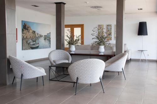 una sala da pranzo con sedie, tavolo e divano di Grupoandria Hotel Platja Gran a Ciutadella