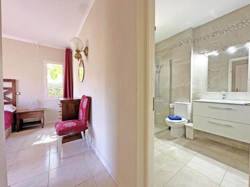 baño con silla roja, lavabo y aseo en Luxury Villa Lucia, en La Playa de Tauro