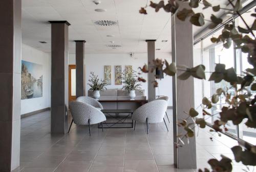 a dining room with white chairs and a table at Grupoandria Hotel Platja Gran in Ciutadella