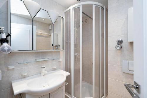ein Bad mit einer Dusche, einem Waschbecken und einem Spiegel in der Unterkunft Strandsonne in List