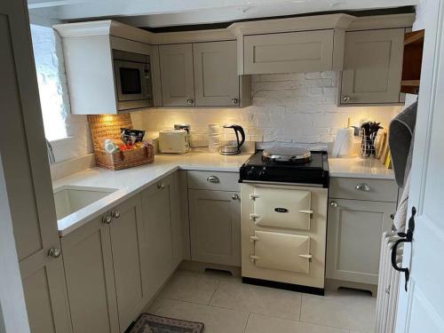 a kitchen with white cabinets and a stove top oven at Woodpecker Cottage in West Bretton