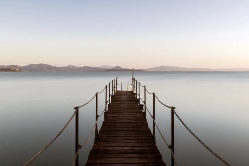 a wooden dock in the middle of a body of water at Hotel Kursaal in Passignano sul Trasimeno