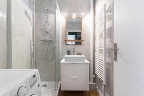La salle de bains blanche est pourvue d'un lavabo et d'une douche. dans l'établissement Joli Appartement avec Garage sur l'Île de Nantes, à Nantes