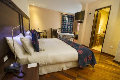 ein Hotelzimmer mit einem großen Bett und einem Tisch in der Unterkunft La Casona de la Ronda Hotel Boutique & Luxury Apartments in Quito