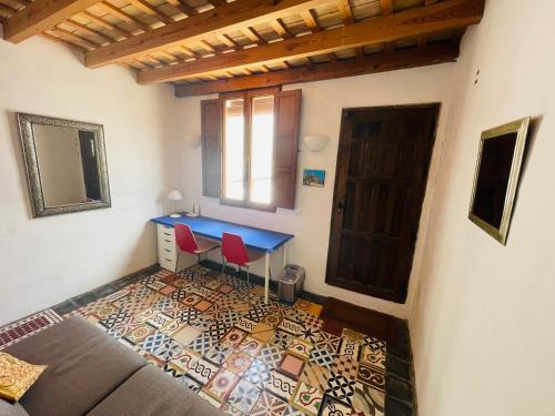 a bedroom with a desk and a bed with red chairs at Casa Patio de Monjas in Vejer de la Frontera