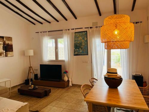 sala de estar con mesa y TV en Primera Linea de Playa, Villa Conchita, con Salida al Mar, en Sagunto