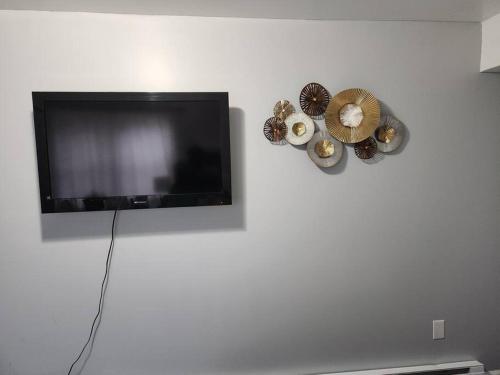 einen Flachbild-TV, der an einer weißen Wand hängt in der Unterkunft Spacious Cozy 2 Bedroom - Near EWR/NYC/OUTLET MALL in Newark