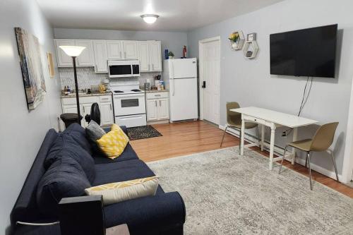 ein Wohnzimmer mit einem blauen Sofa und einer Küche in der Unterkunft Spacious Cozy 2 Bedroom - Near EWR/NYC/OUTLET MALL in Newark