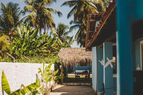 een huis met een blauwe deur en palmbomen bij 4 quartos ao lado da praia do Patacho in Pôrto de Pedras