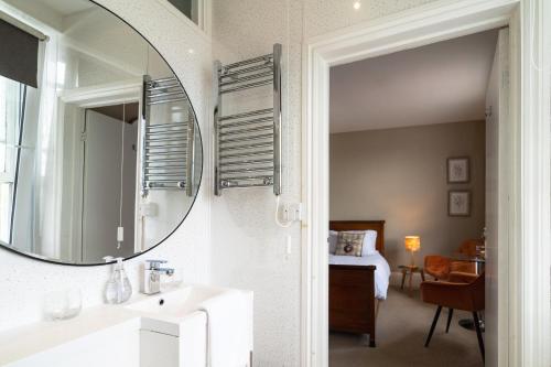 a bathroom with a mirror and a bedroom with a bed at Sleepy Puffin Guest House in Tenby