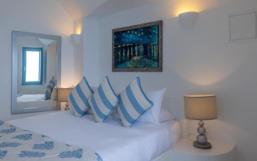 a bedroom with a bed with blue and white pillows at Above Blue Suites in Imerovigli