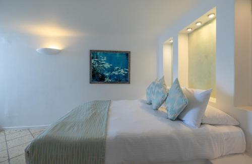 a bedroom with a large white bed with blue pillows at Above Blue Suites in Imerovigli