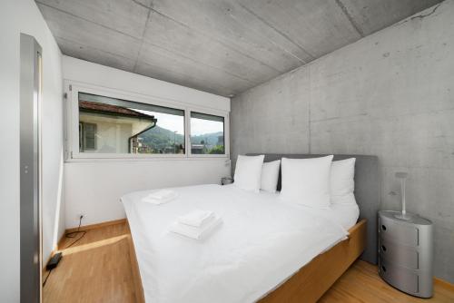 a bedroom with a large white bed with a window at Urban Cube mit Sauna in Thun