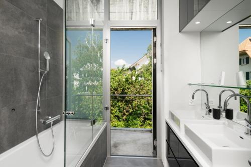 a bathroom with two sinks and a shower with a glass door at Urban Cube mit Sauna in Thun