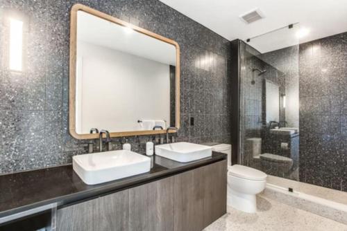 baño con 2 lavabos, espejo y aseo en 2 BR Lux Panoramic View - Rainey en Austin