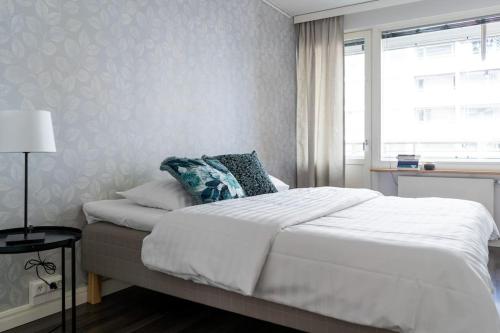 1 dormitorio con 1 cama blanca y ventana en Spacious 2br Apartment in the City Center, en Tampere