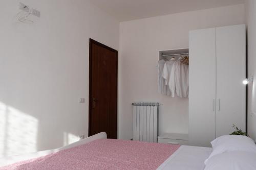 a white bedroom with a pink bed and a closet at App.Carrera Fondi in Fondi