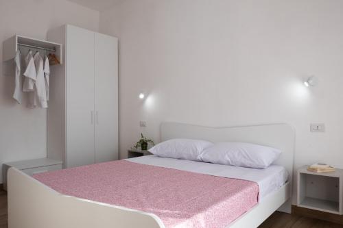 - une chambre avec un lit blanc et une couverture rose dans l'établissement App.Carrera Fondi, à Fondi