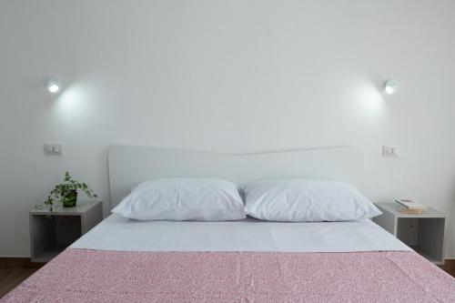 - un lit blanc avec 2 oreillers et 2 tables dans l'établissement App.Carrera Fondi, à Fondi