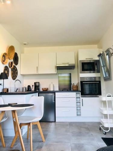 une cuisine avec des armoires blanches et une table et des chaises dans l'établissement Bel Air Studios-Terrasse couverte-Jardinet-Vue Pont de Normandie-Parking privé, à Honfleur