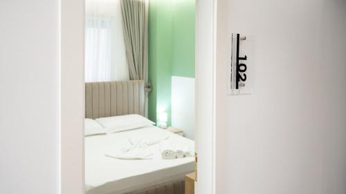 a bedroom with a white bed and a green wall at Hotel Luris in Golem