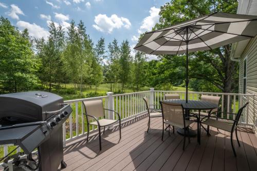 a deck with a grill and a table with chairs and an umbrella at Happy Ours in McHenry
