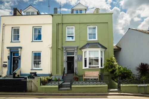 a green house with a bench in front of it at Sleepy Puffin Guest House in Tenby