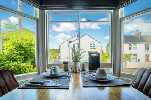 a dining room with a table and a large window at Sleepy Puffin Guest House in Tenby