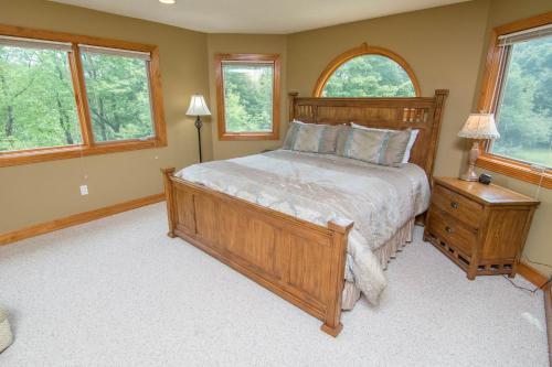 Schlafzimmer mit einem großen Holzbett und Fenstern in der Unterkunft Marsh Run Cove in McHenry