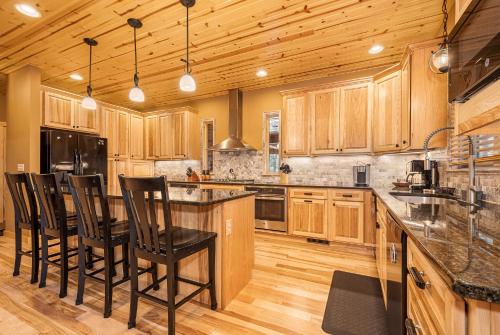 a kitchen with wooden cabinets and black bar stools at Claralea Lodge in Oakland