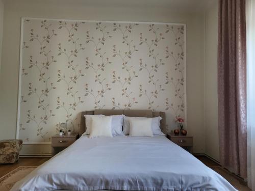 1 dormitorio con 1 cama grande y papel pintado con motivos florales en Pandora Guest House en Cluj-Napoca
