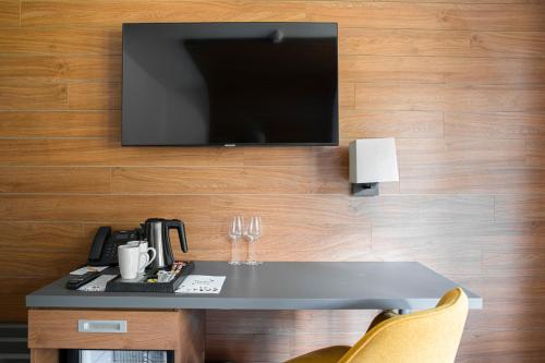 a tv on a wall with a table and chairs at Amenity Hotel & Resort Orlické hory in Deštné v Orlických horách