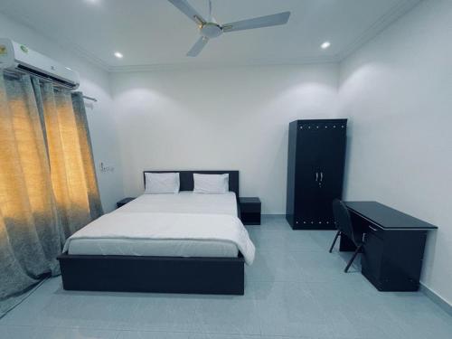 Rakka Guest House في Adentan: غرفة نوم بسرير ومكتب ونافذة