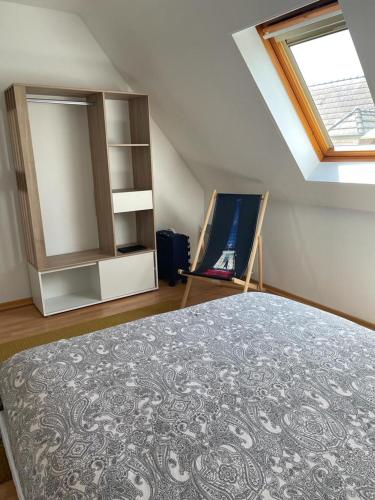 Cette chambre mansardée comprend un lit et une fenêtre. dans l'établissement Gîte Au nid de cigognes, à Leutenheim