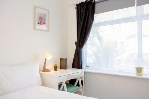 a bedroom with a bed and a desk and a window at Stylish 4BD House with Private Garden - Stratford in London